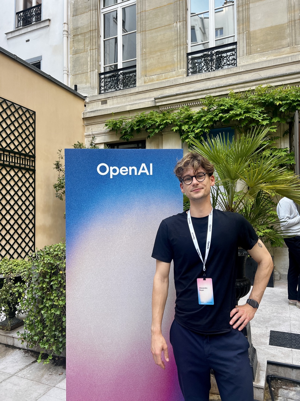 Alex, fondateur d’AI-Driven Dev, devant la signalétique OpenAI lors d’un événement